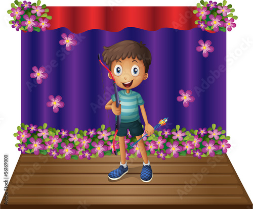A stage with a young boy holding a bow and arrow