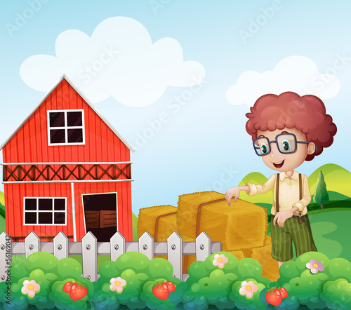 A young boy standing near the hays in the farm