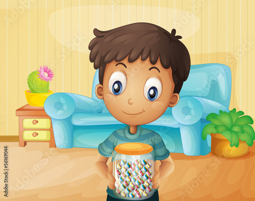 A boy inside the house with a jar of candies