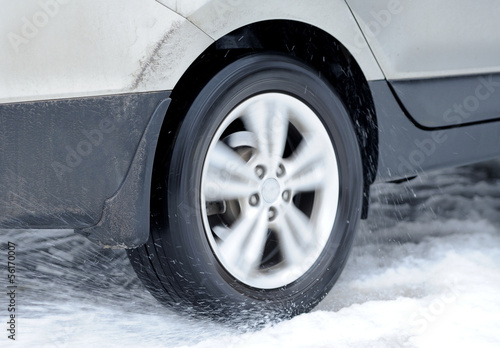 Dirty car wheel stands on winter road © byrdyak