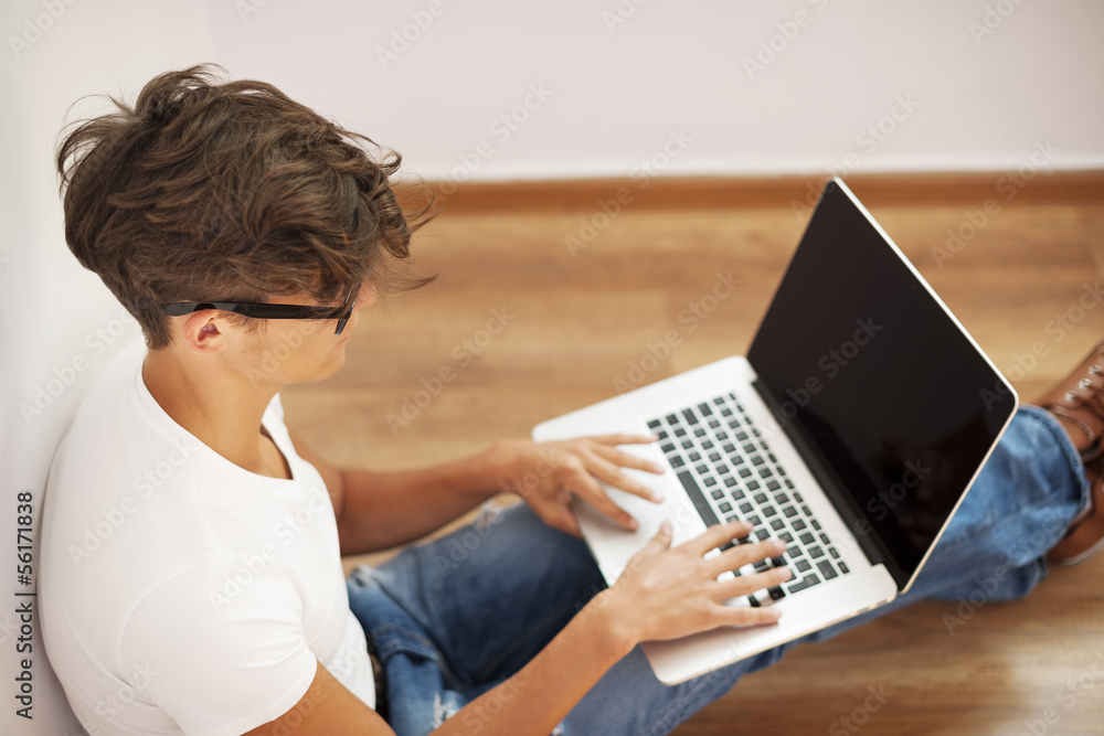 Fototapeta premium Young man looking thoughtful and using laptop