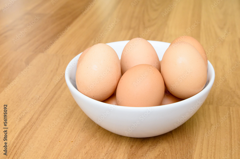 Eggs in white bowl on wooden table Eggs in white bowl on wooden table