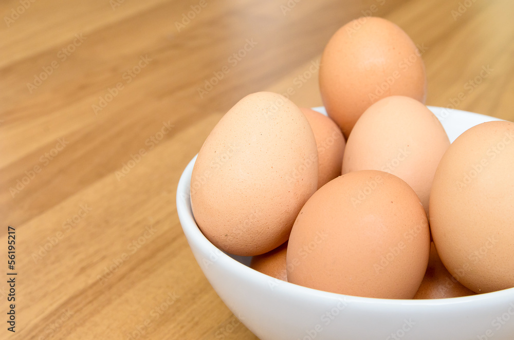 Eggs in white bowl on wooden table Eggs in white bowl on wooden table