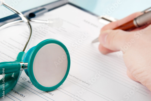 Doctor filling in medical questionnaire form in a clipboard