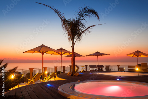 Summer time: beautiful view of red dawn at pool area with palm a