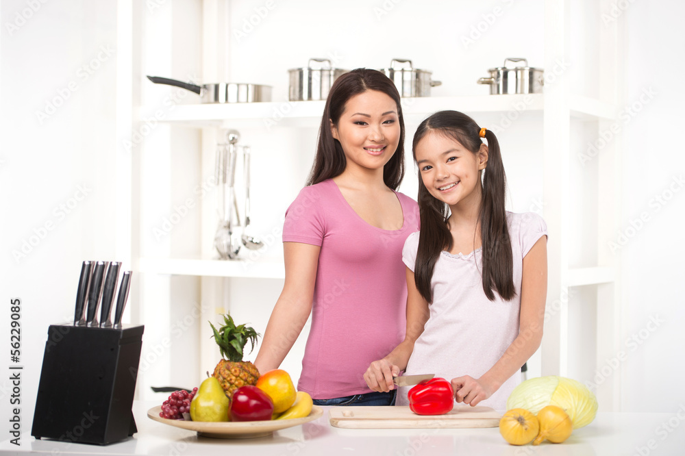 Mother and daughter on the kitchen. Cheerful daughter helping he