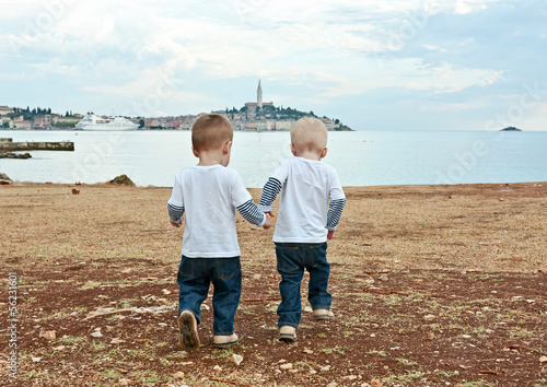 Twins go by a hand on a beach in the evening. Rovinj. Croatia.