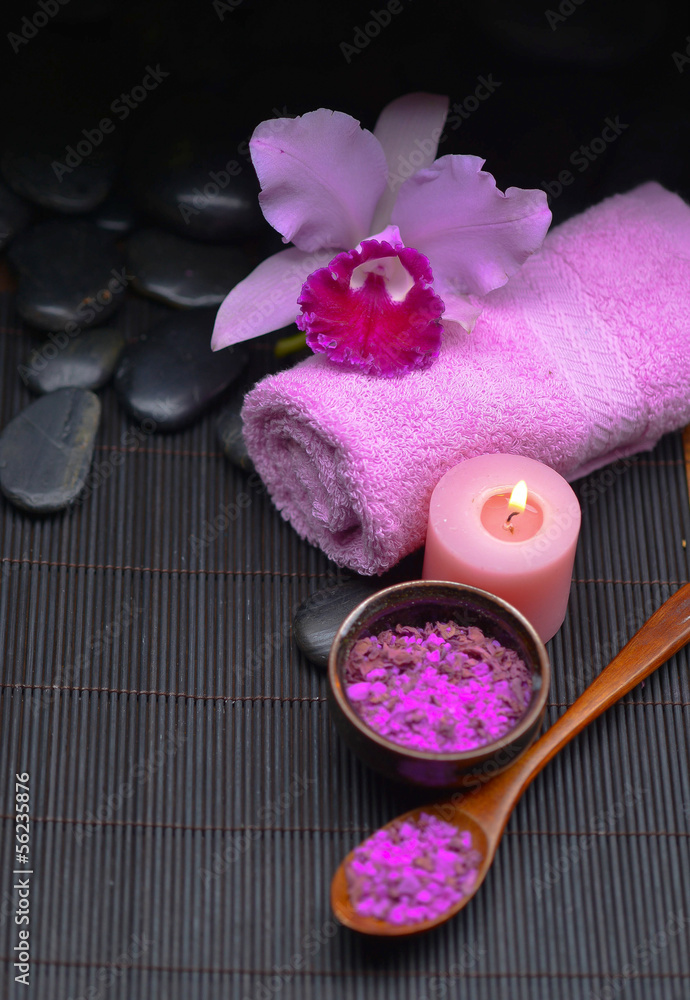 pink orchid on towel and stones ,candle, salt in bowl on mat pink orchid on towel and stones ,candle, salt in bowl on mat