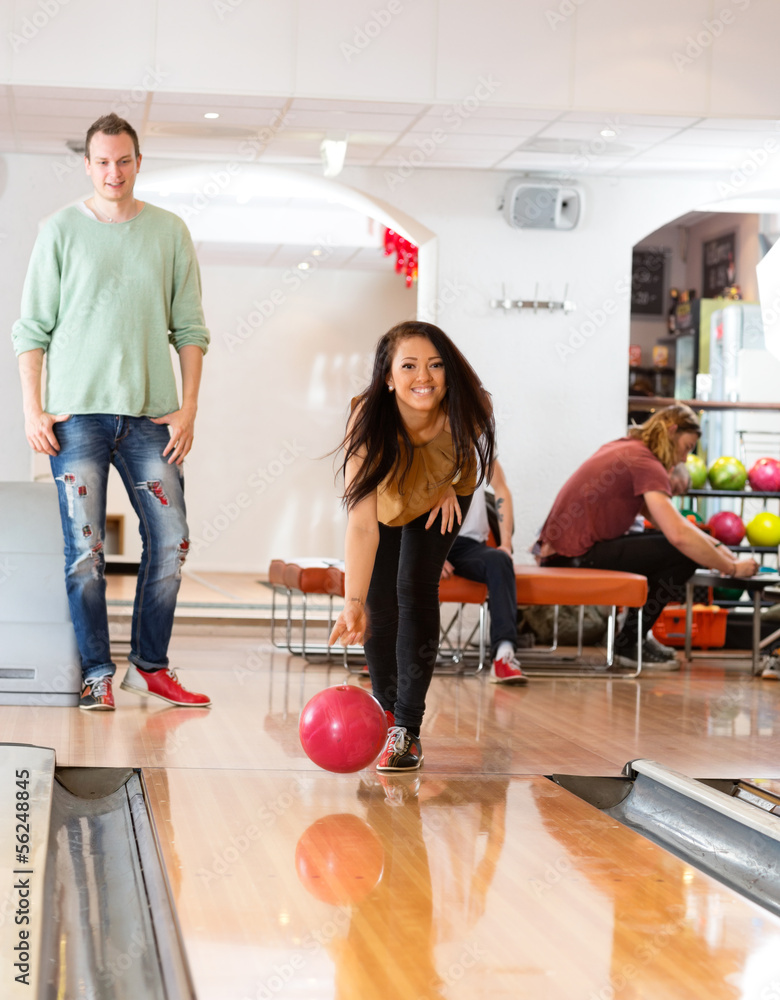 Obraz premium Happy Young Woman Bowling in Club