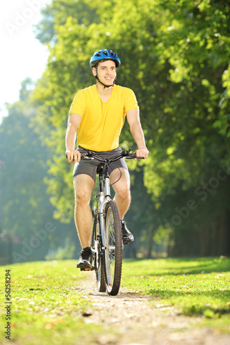 Full length portrait of a young man biking in a park