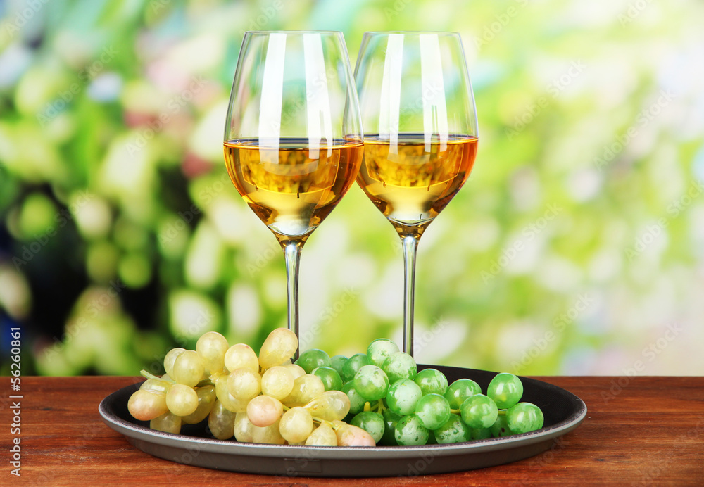 Ripe grapes and glasses of wine, on bright background