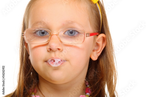 Close up little girl in glasses doing fun saliva bubbles photo