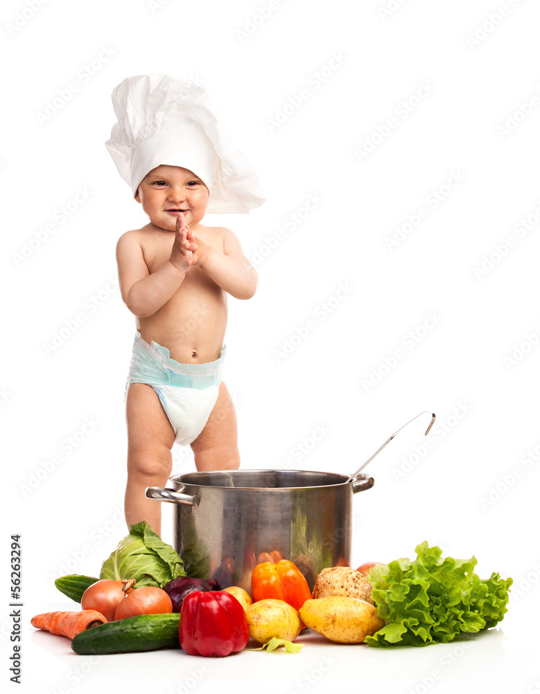 Little boy in chef's hat standing among fresh vegetables Little boy in chef's hat standing among fresh vegetables