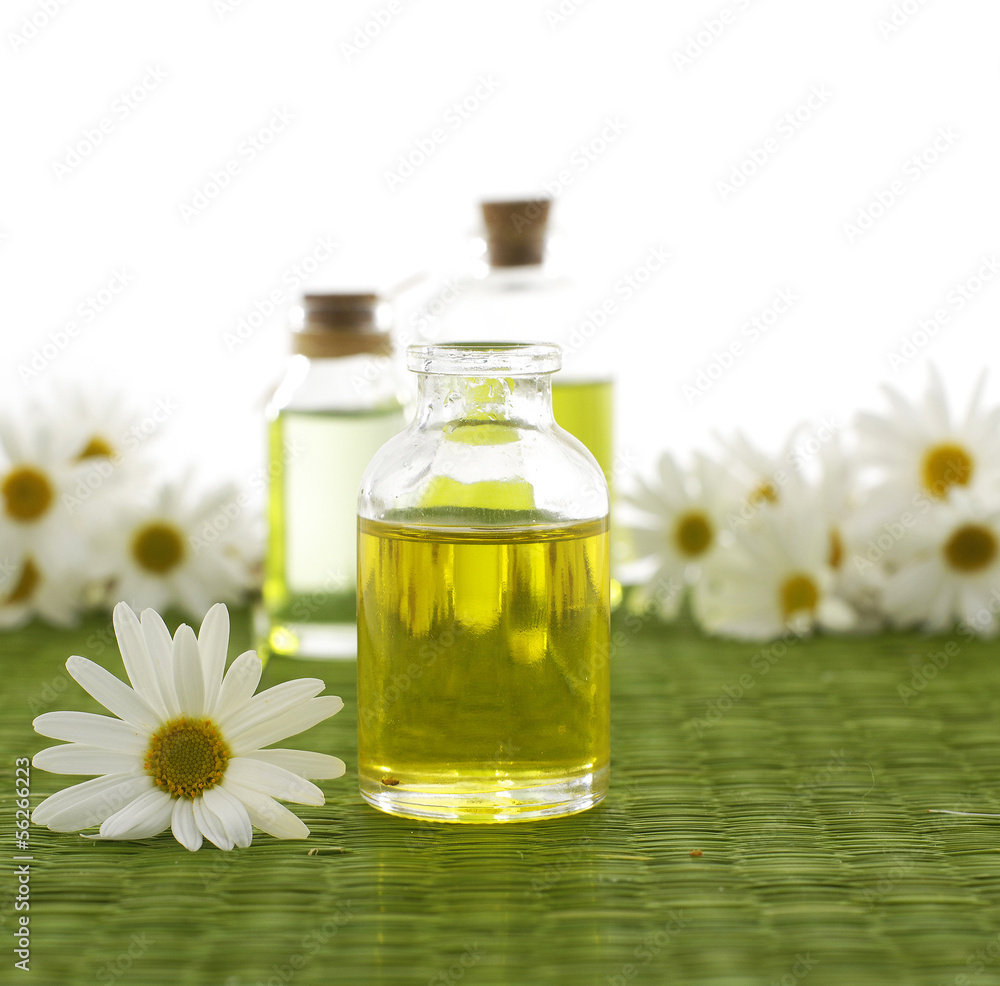 Glass Bottle with daisy flowers on green mat Glass Bottle with daisy flowers on green mat