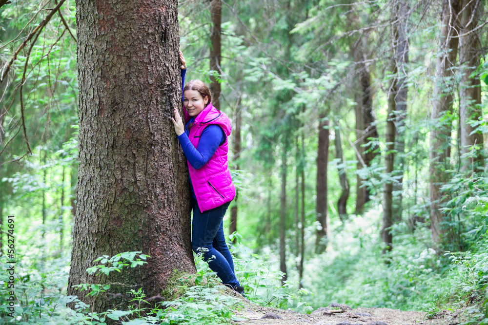 Tranquil young woman standing cheek to tree stem in forest Tranquil young woman standing cheek to tree stem in forest