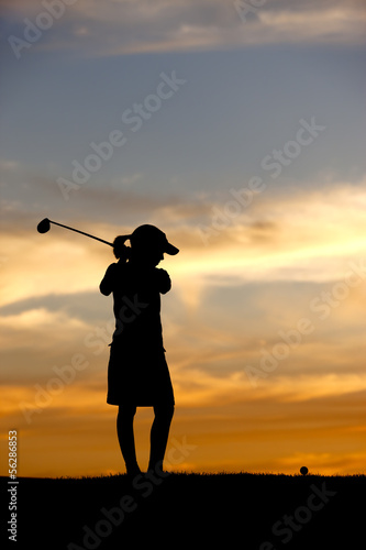 Silhouetted girl swings driver.
