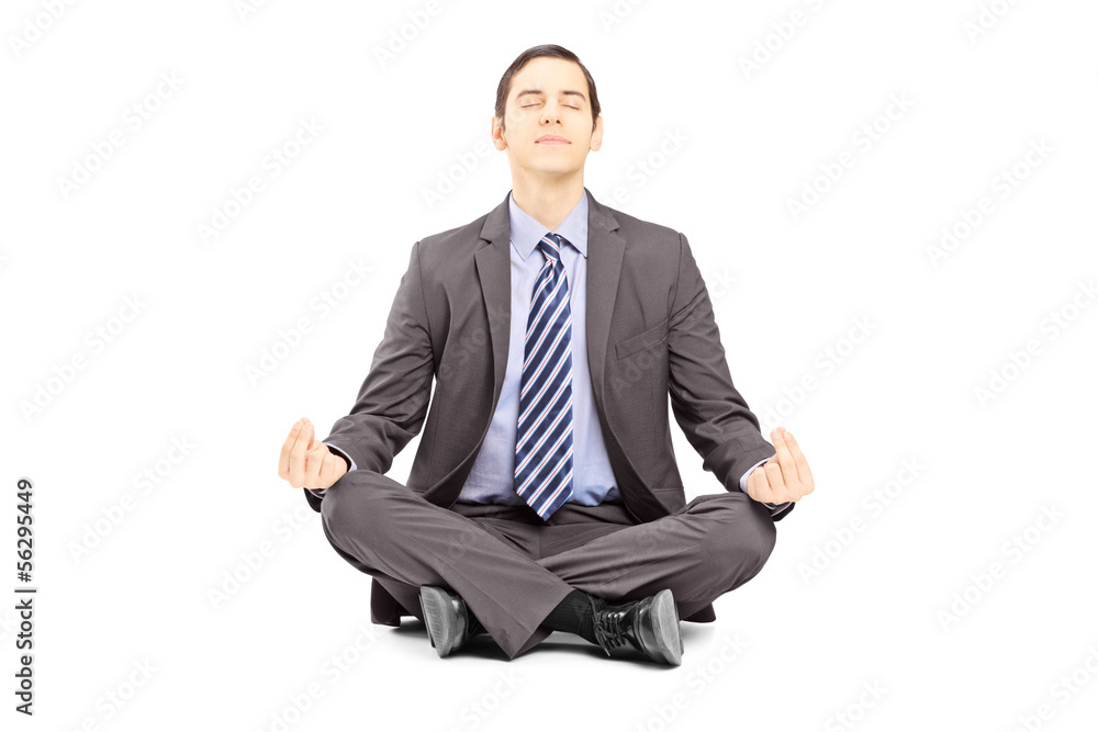 Young businessman in suit sitting on a floor and meditating Young businessman in suit sitting on a floor and meditating