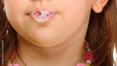 Close up little girl doing fun saliva bubbles photo