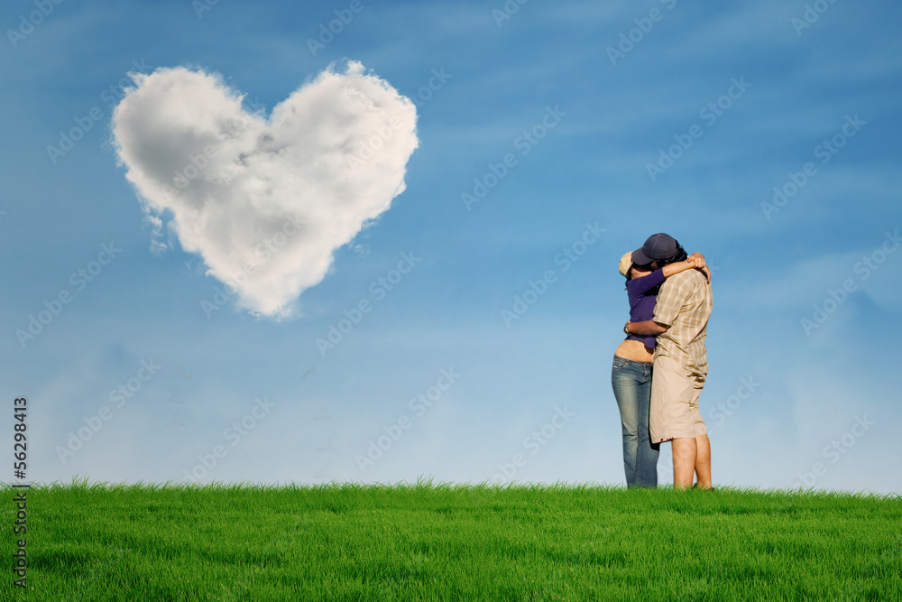 Couple kissing under heart shape cloud