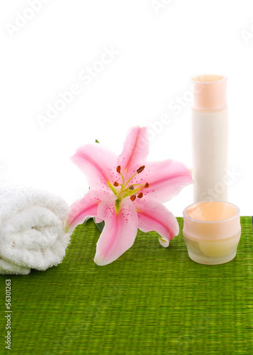 Pink lily with massage oil and roller towel on green mat