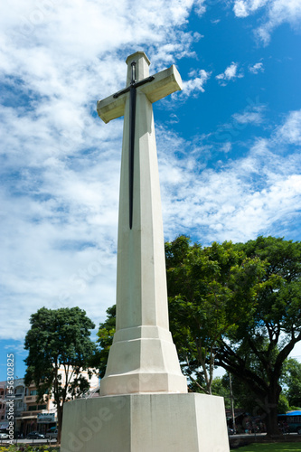 White cross against blue sky and fluffy clouds