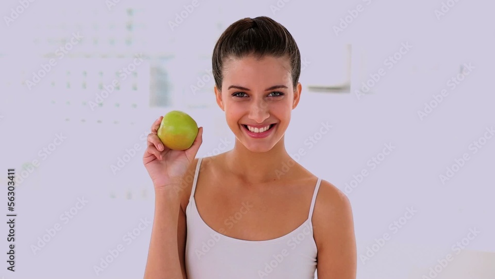 Amused woman smelling and showing an apple Amused woman smelling and showing an apple