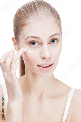 young blond woman applying facial creme