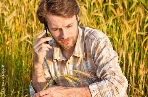 Farmer control wheat field while talking on mobile phone
