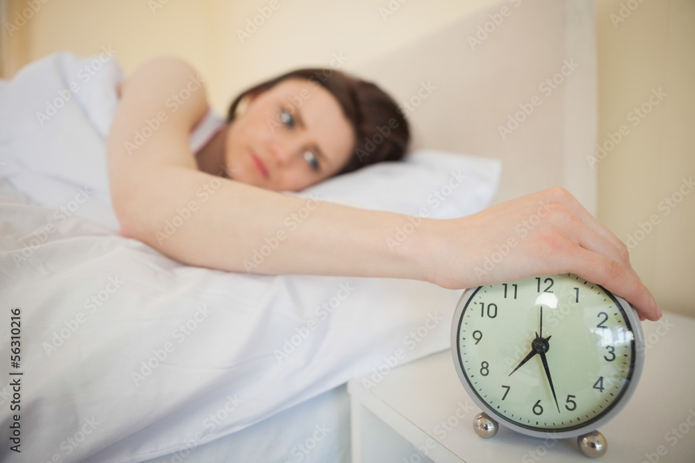 Tired girl turning off her alarm clock Tired girl turning off her alarm clock