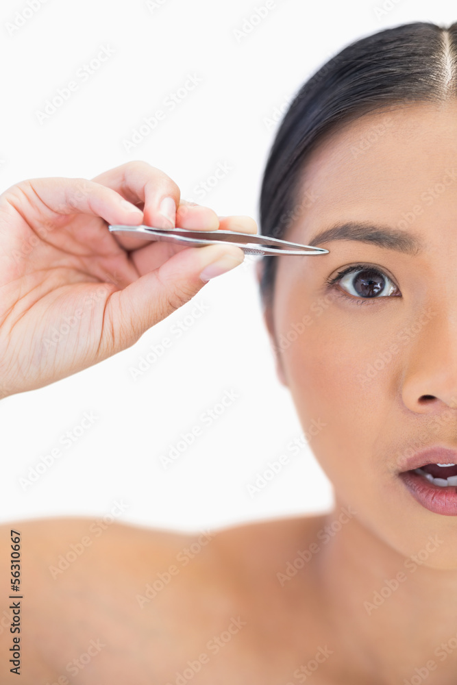 Half face of surprised natural woman using tweezers