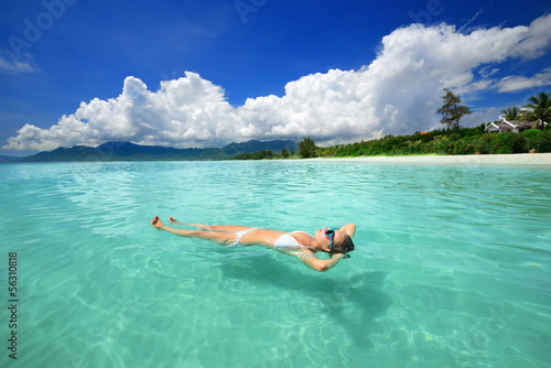 Woman in bikini relaxing lying on the water against the backgrou