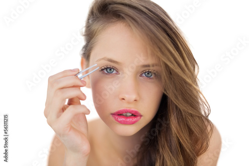 Concentrated brunette model plucking her eyebrows