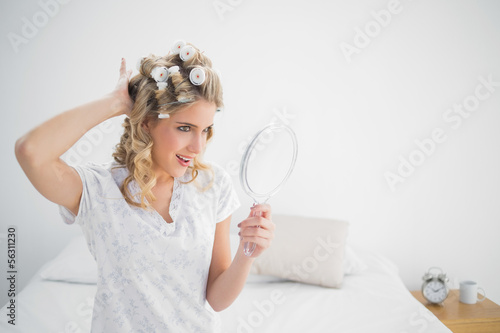 Cheerful gorgeous blonde wearing hair curlers posing