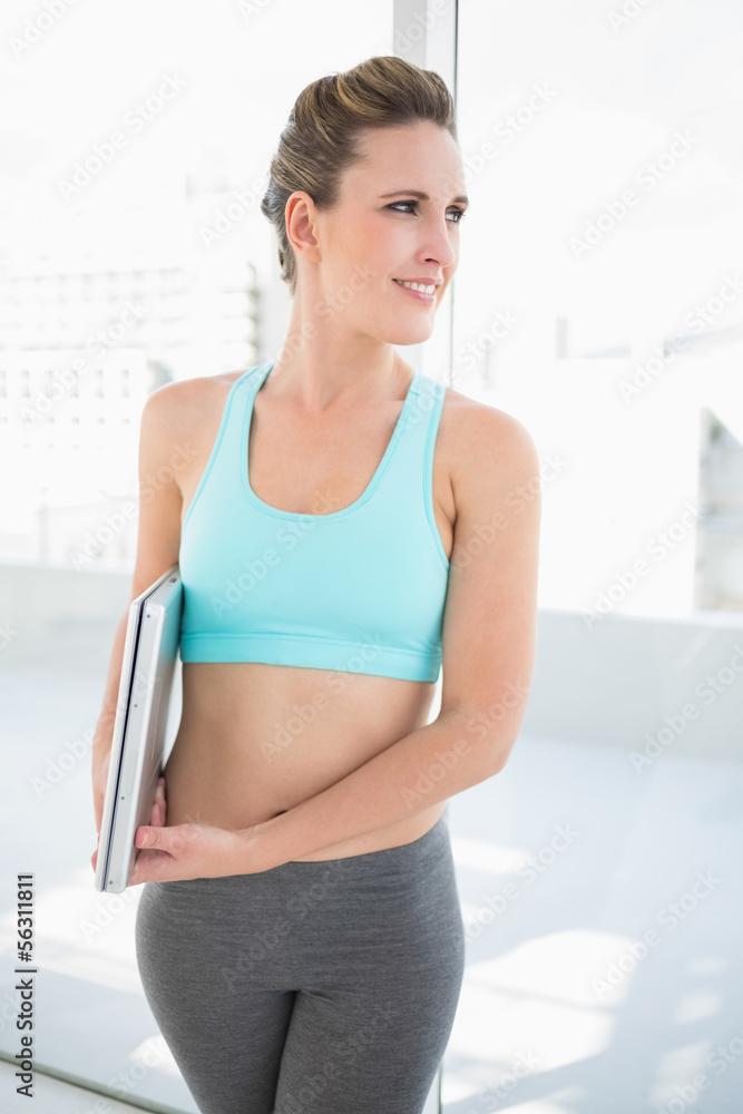 Smiling woman in sportswear holding laptop