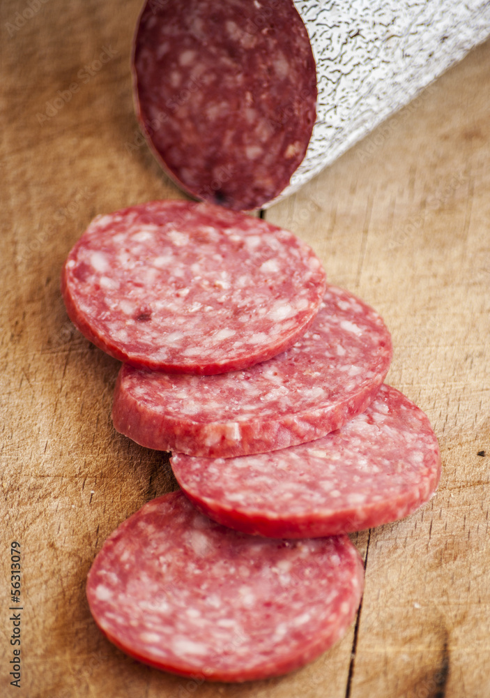 Fresh pork salami on wooden background close up Fresh pork salami on wooden background close up