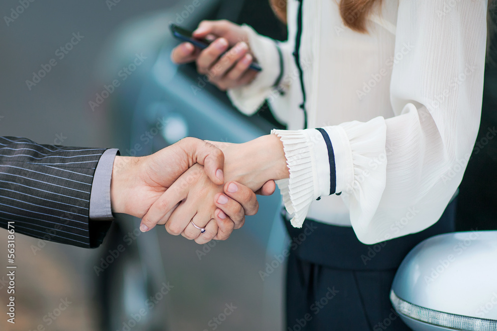 Obraz premium Business transaction, she shakes hands with a man buying a car