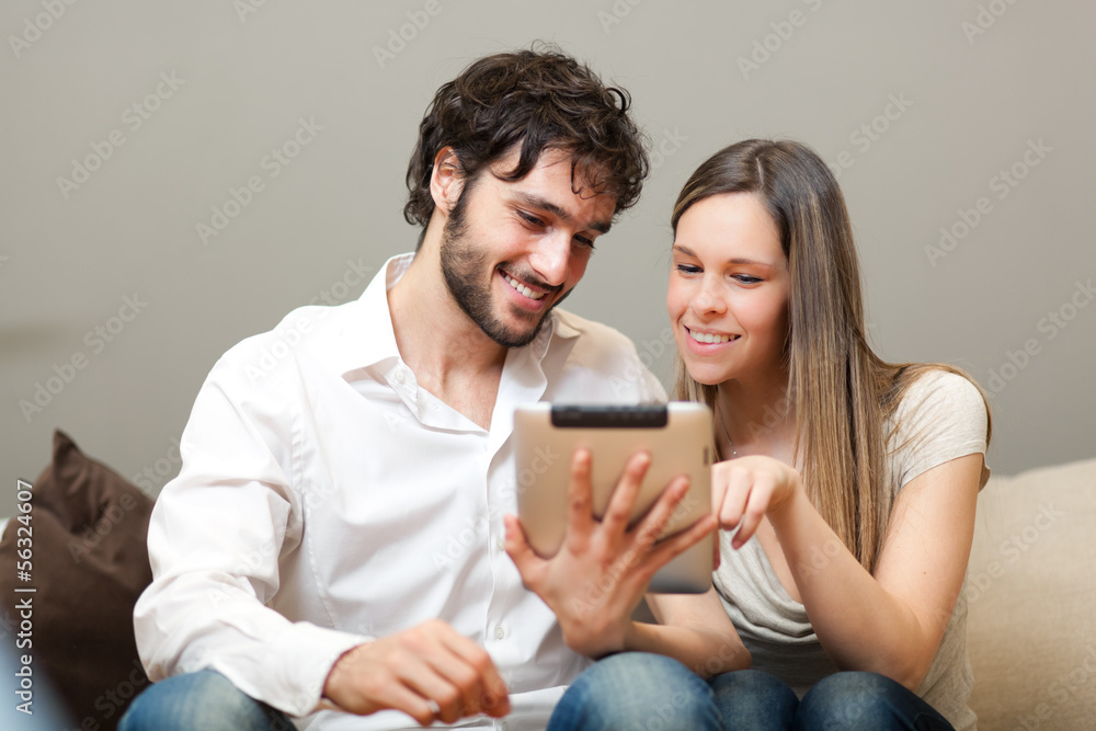 In love couple using a tablet computer in their living room In love couple using a tablet computer in their living room