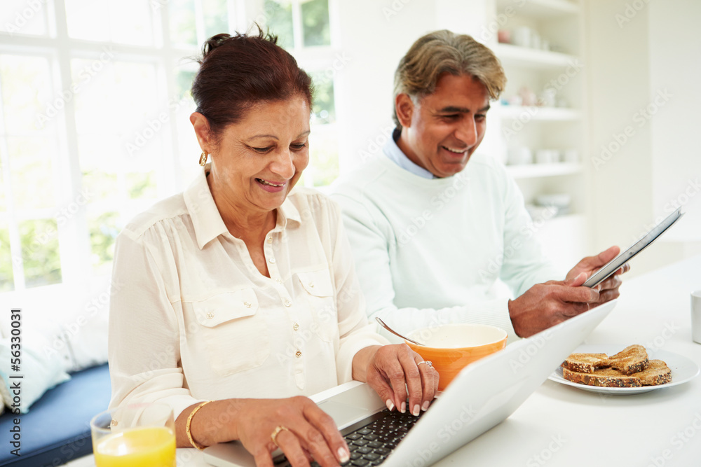 Senior Indian Couple Using Laptop And Digital Tablet At Home Senior Indian Couple Using Laptop And Digital Tablet At Home