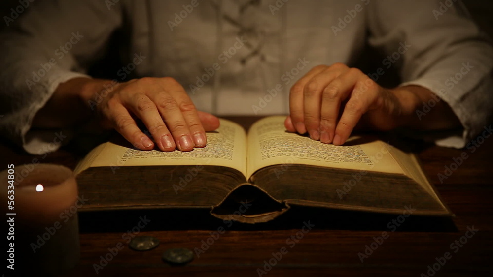 medieval looking man is reading a old book and lifts thumb up