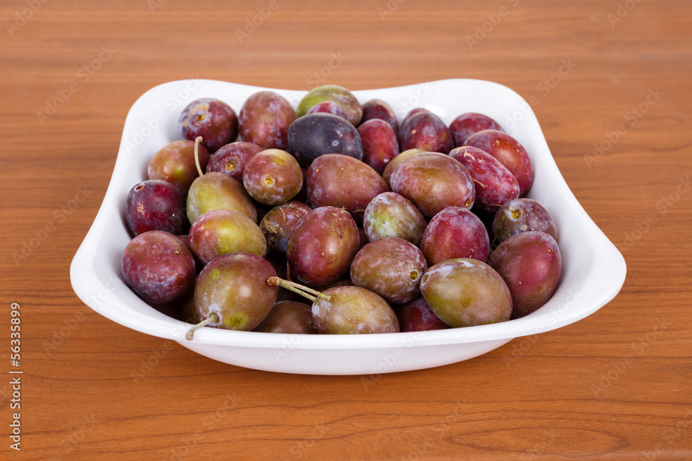 Obraz premium Acid purple and green Plums (Blackthorns)in bowl