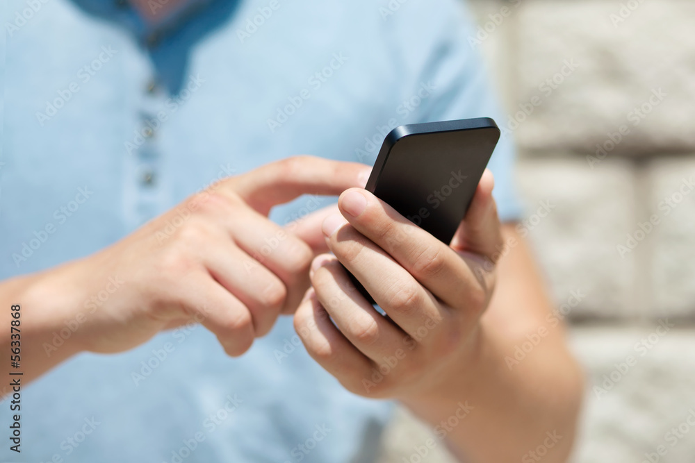 boy holding a phone and a touch screen for finger against a wall