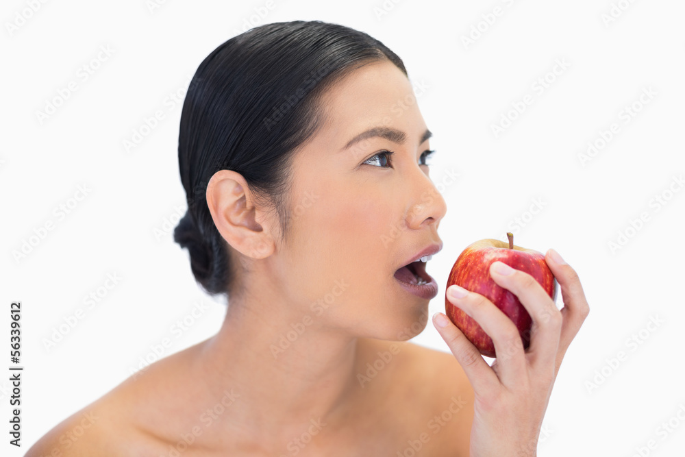 Thoughtful black haired model eating red apple Thoughtful black haired model eating red apple