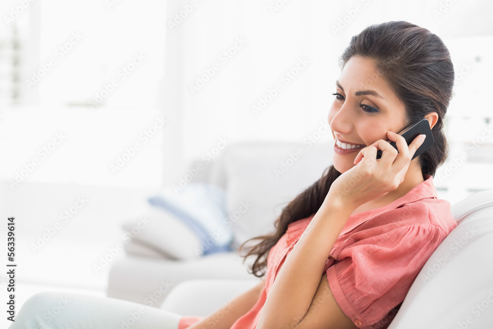 Content brunette sitting on her sofa on the phone Content brunette sitting on her sofa on the phone