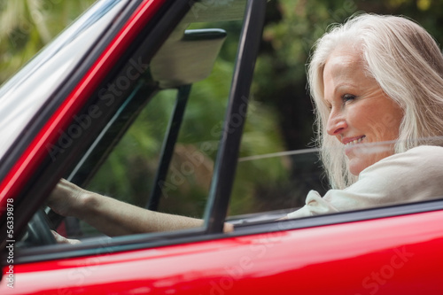 Cheerful mature woman driving red convertible © WavebreakMediaMicro
