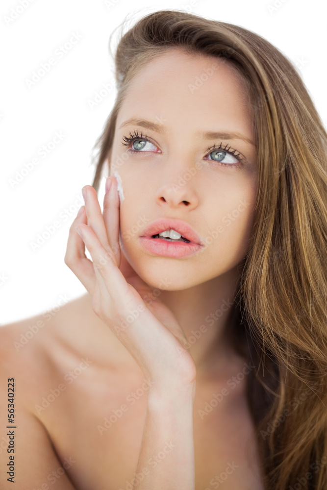 Concentrated brunette model rubbing her cheek with cream Concentrated brunette model rubbing her cheek with cream