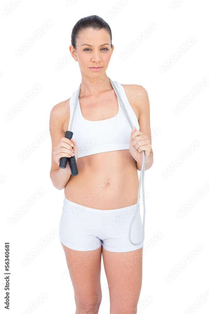 Serious fit sportswoman holding skipping rope around neck Serious fit sportswoman holding skipping rope around neck