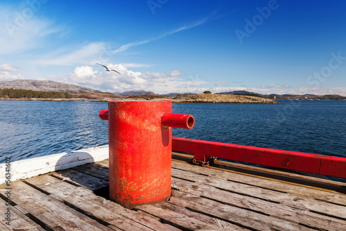 Red mooring bollard on wooden pier in Norway