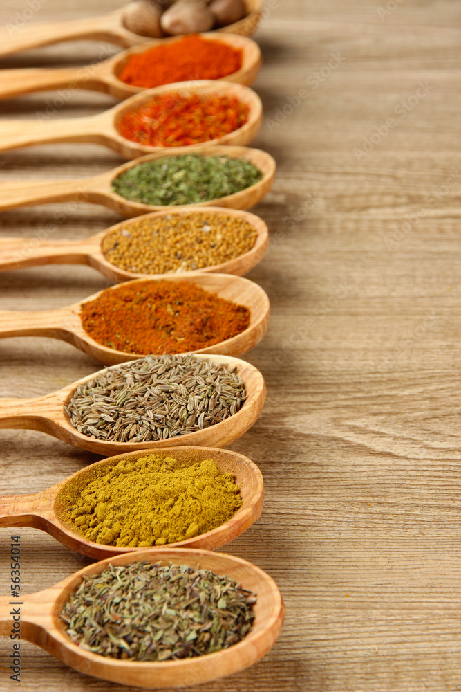 Assortment of spices in wooden spoons on wooden background