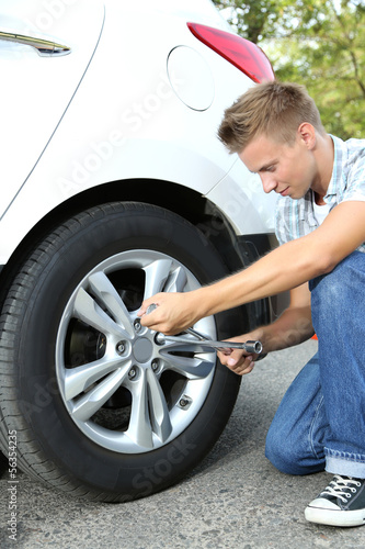 Man driver having trouble at road changing wheel