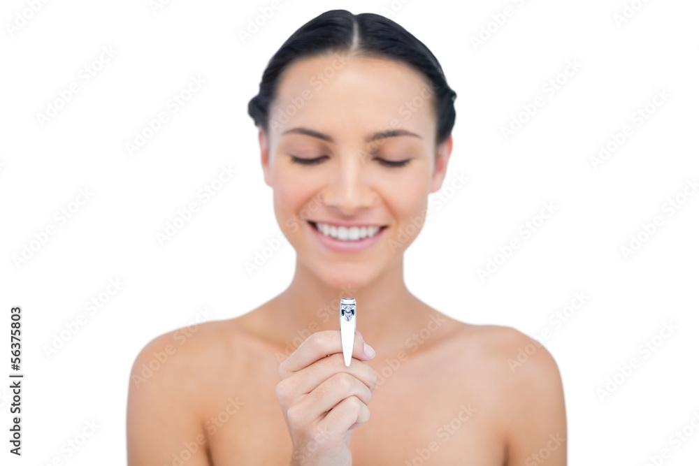 Happy brunette holding and looking at her nail clippers Happy brunette holding and looking at her nail clippers